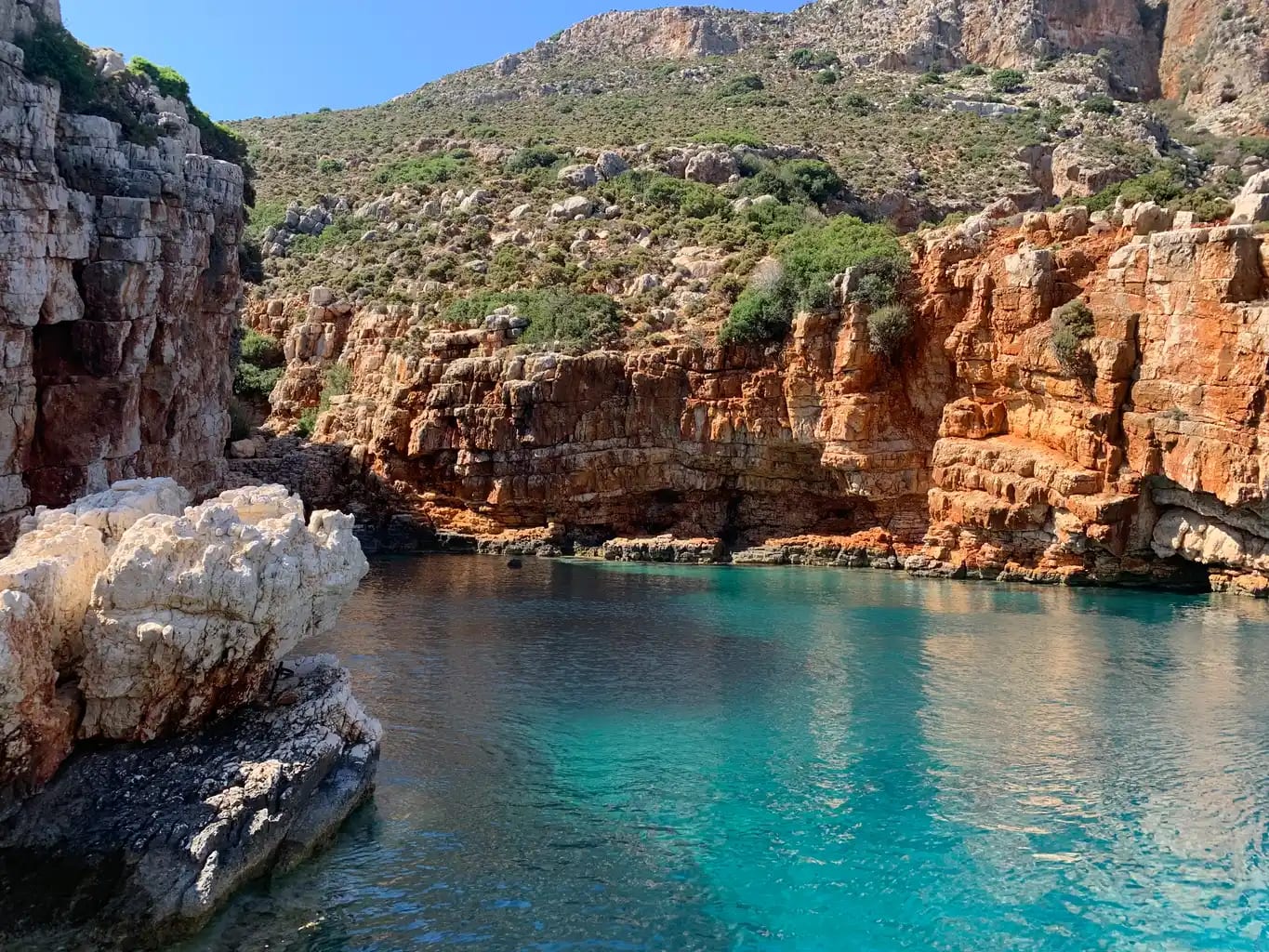 Návlakas Bay — turquoise water and red-rock cliffs